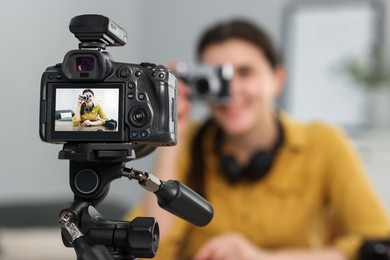 Photo of Technology blogger explaining something while recording video at home, focus on camera