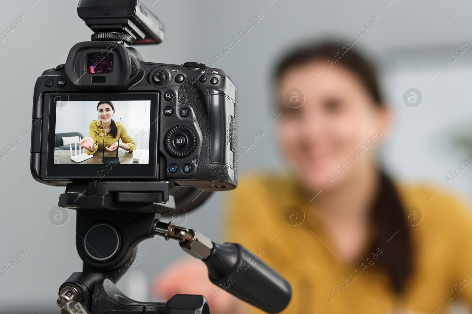 Photo of Technology blogger explaining something while recording video at home, focus on camera