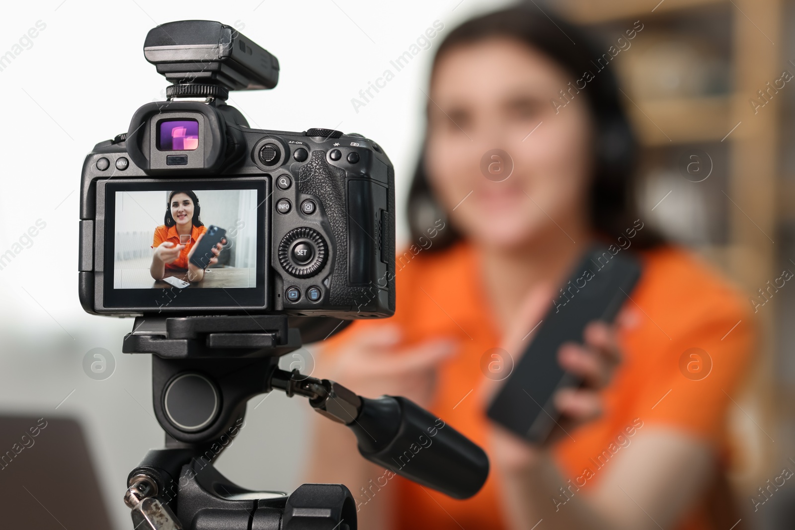 Photo of Technology blogger explaining something while recording video at home, focus on camera