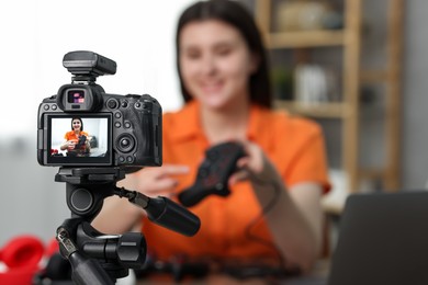 Photo of Technology blogger explaining something while recording video at home, focus on camera