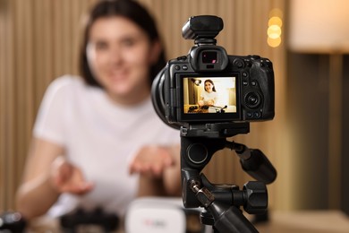 Photo of Technology blogger explaining something while recording video at home, focus on camera