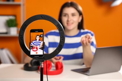 Photo of Technology blogger explaining something while recording video at home, focus on smartphone