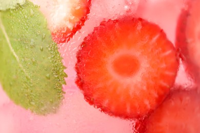 Freshly made strawberry lemonade with mint in jug as background, closeup