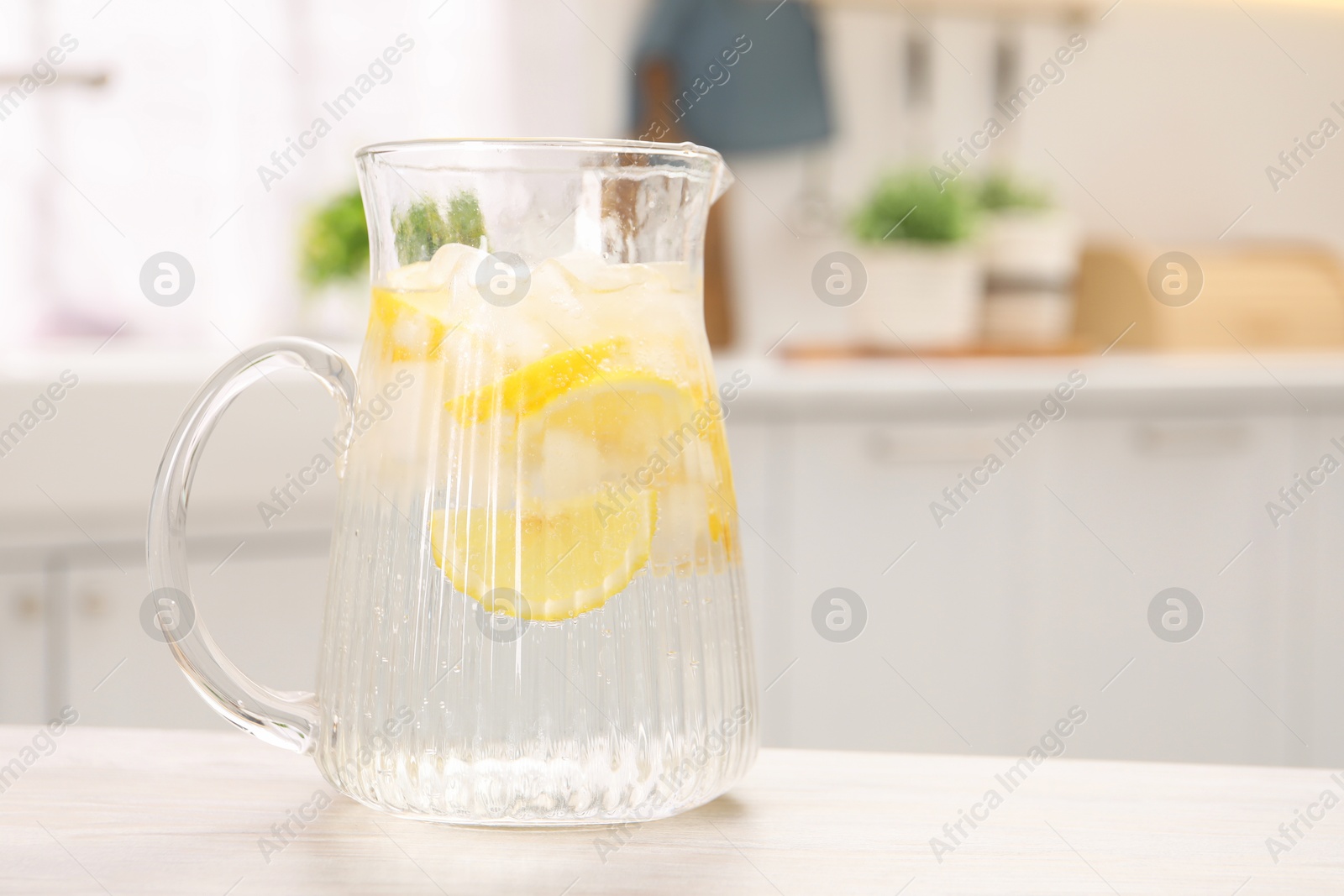 Photo of Freshly made lemonade in jug on white wooden table indoors, space for text