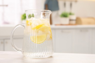 Freshly made lemonade in jug on white wooden table indoors, space for text