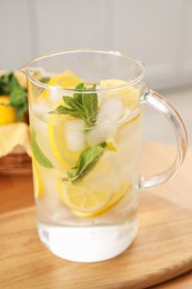 Freshly made lemonade with mint in jug on wooden table indoors