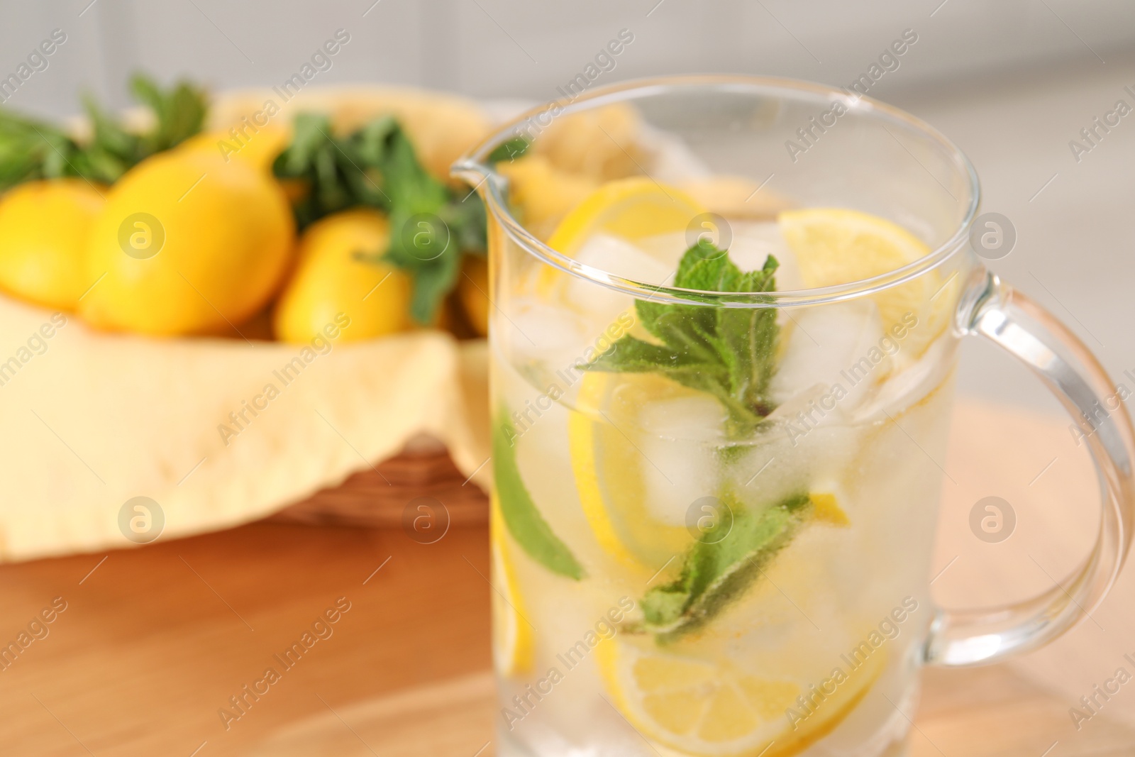 Photo of Freshly made lemonade with mint in jug on wooden table indoors, closeup