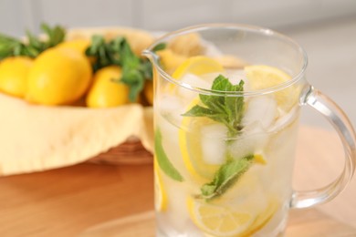 Photo of Freshly made lemonade with mint in jug on wooden table indoors, closeup