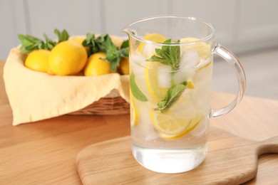 Photo of Freshly made lemonade with mint in jug on wooden table indoors