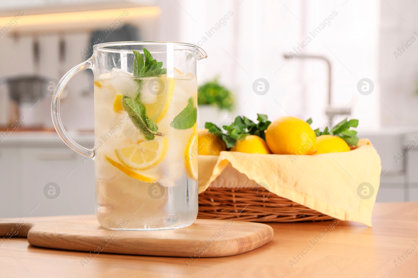 Photo of Freshly made lemonade with mint in jug on wooden table indoors