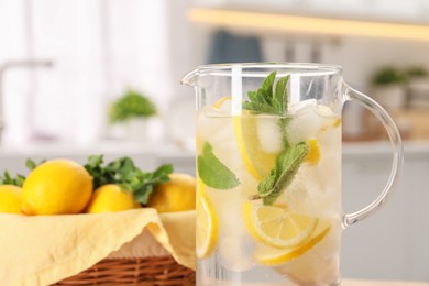 Freshly made lemonade with mint in jug on table indoors, closeup