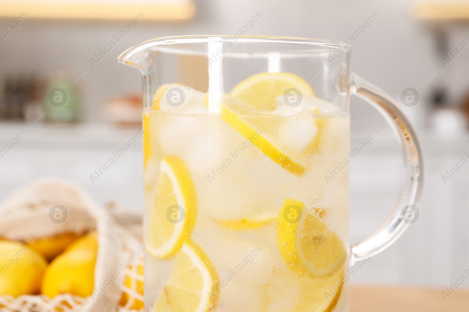 Photo of Freshly made lemonade in jug on table indoors, closeup