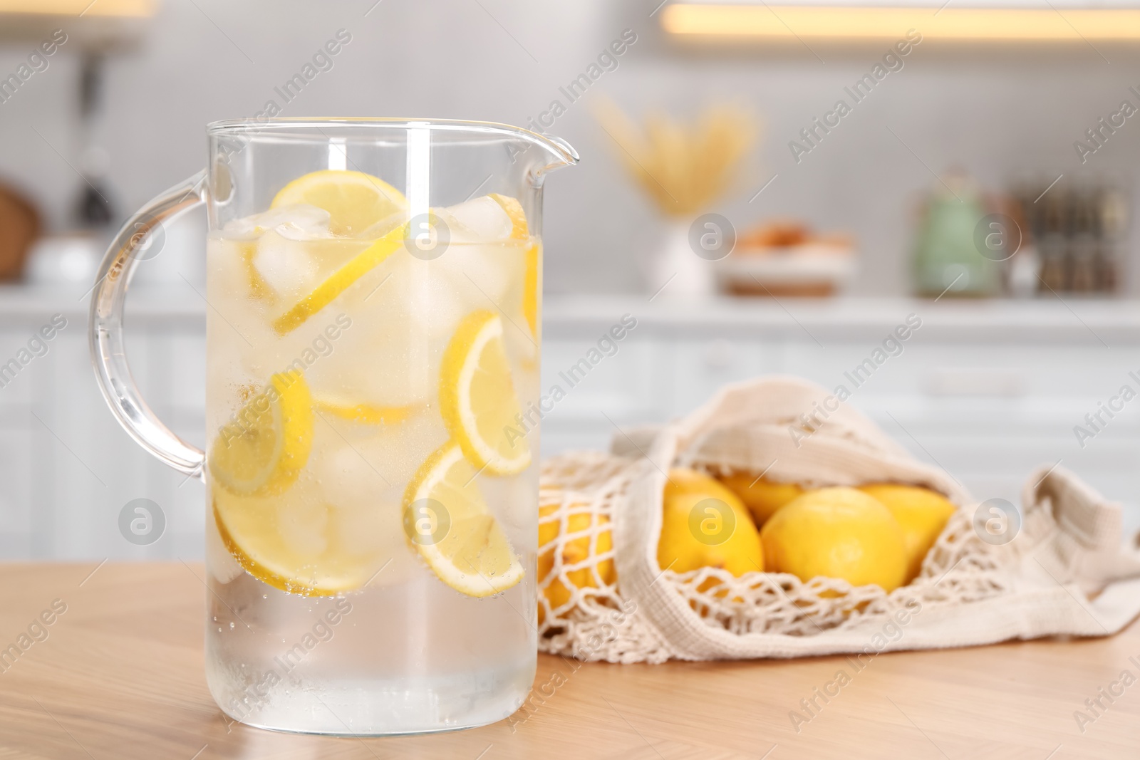 Photo of Freshly made lemonade in jug on wooden table indoors