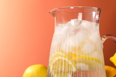 Photo of Freshly made lemonade in jug on orange background, closeup. Space for text