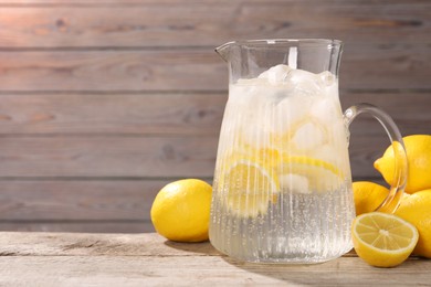 Freshly made lemonade in jug on wooden table, space for text