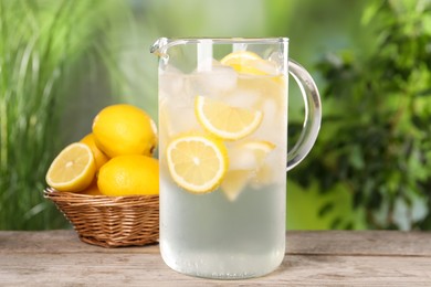 Photo of Freshly made lemonade in jug on wooden table outdoors