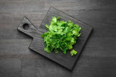 Bunch of fresh coriander on black wooden table, top view