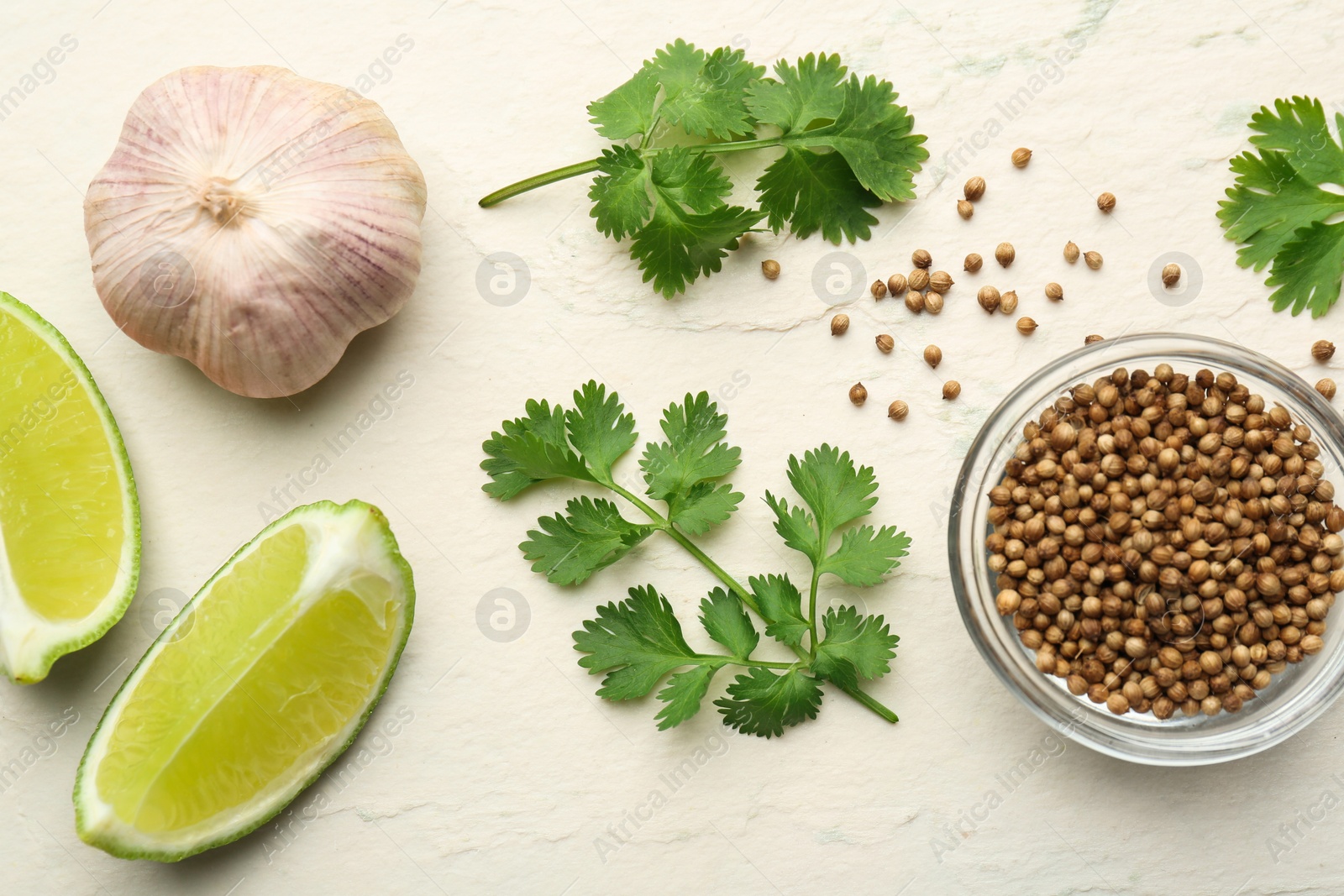 Photo of Fresh coriander leaves, dried seeds, garlic and lime wedges on light textured table, flat lay