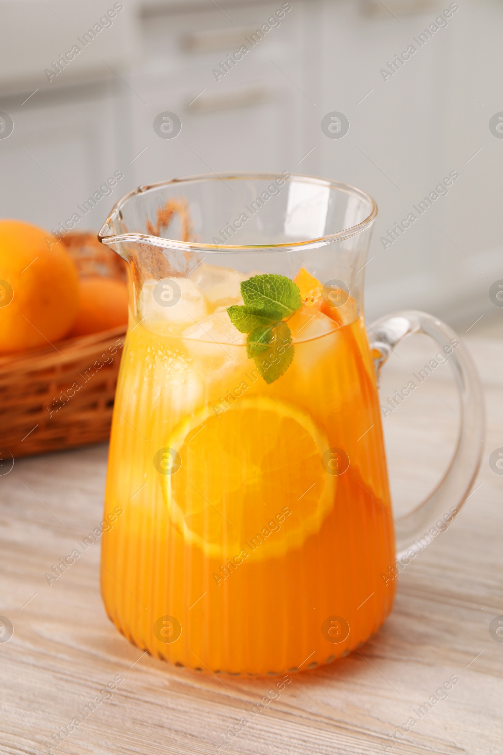 Photo of Freshly made lemonade in jug on wooden table in kitchen