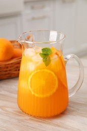 Photo of Freshly made lemonade in jug on wooden table in kitchen