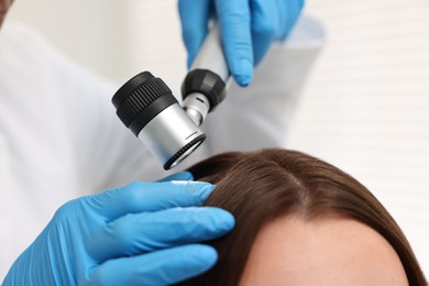 Photo of Trichologist with dermatoscope examining patient`s hair in clinic, closeup