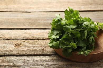 Bunch of fresh coriander on wooden table, space for text