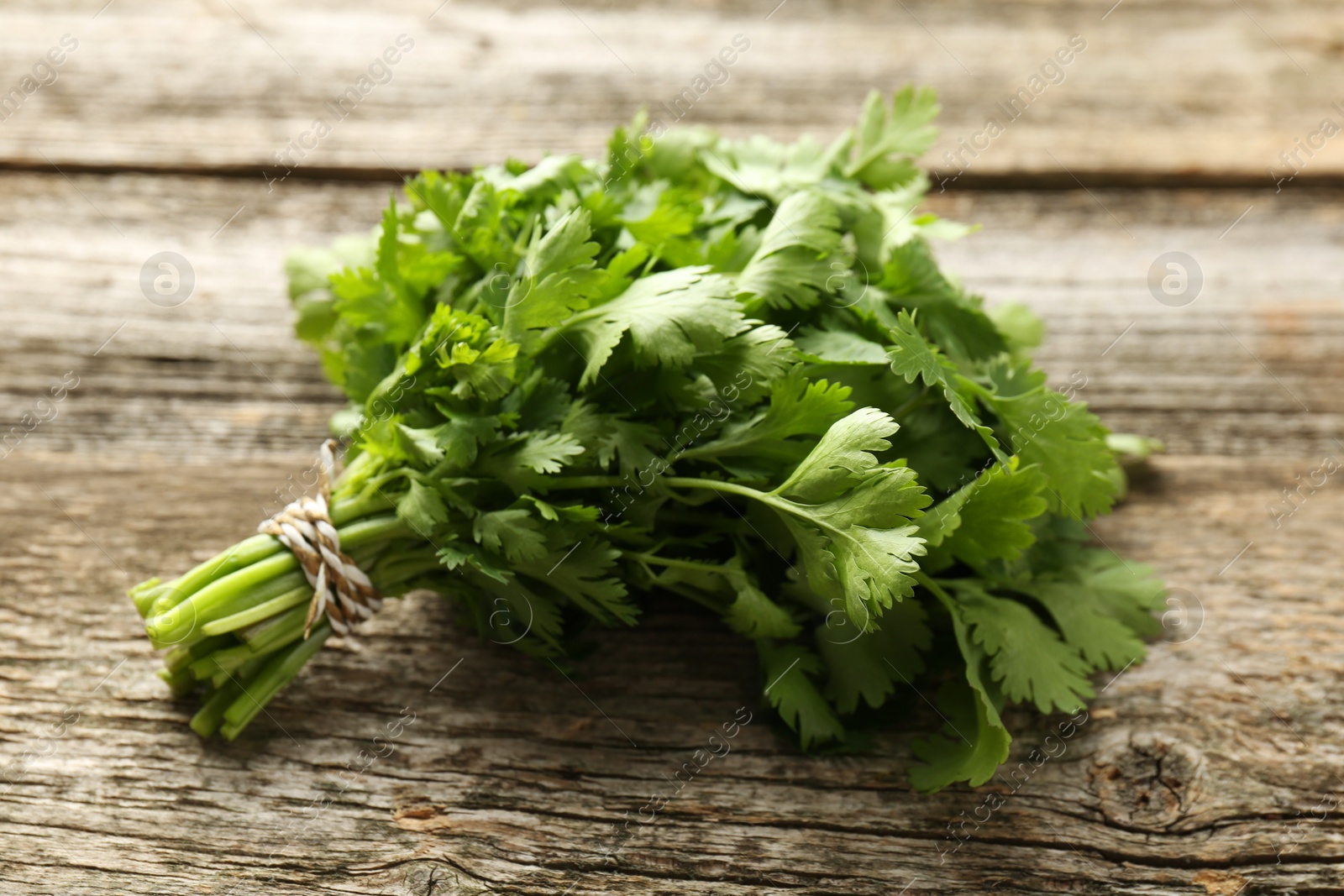 Photo of Bunch of fresh coriander on wooden table, closeup