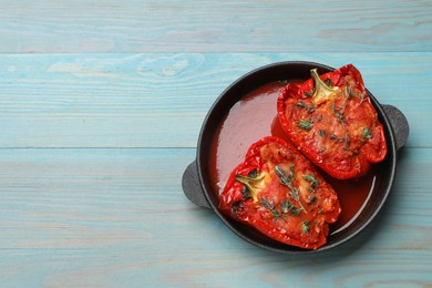 Photo of Tasty stuffed peppers in dish on light blue wooden table, top view. Space for text