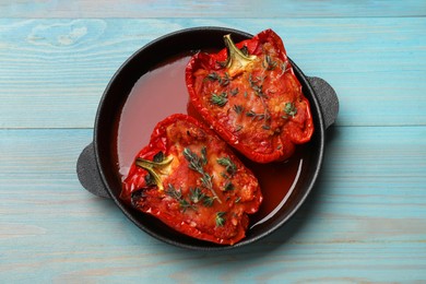 Photo of Tasty stuffed peppers in dish on light blue wooden table, top view