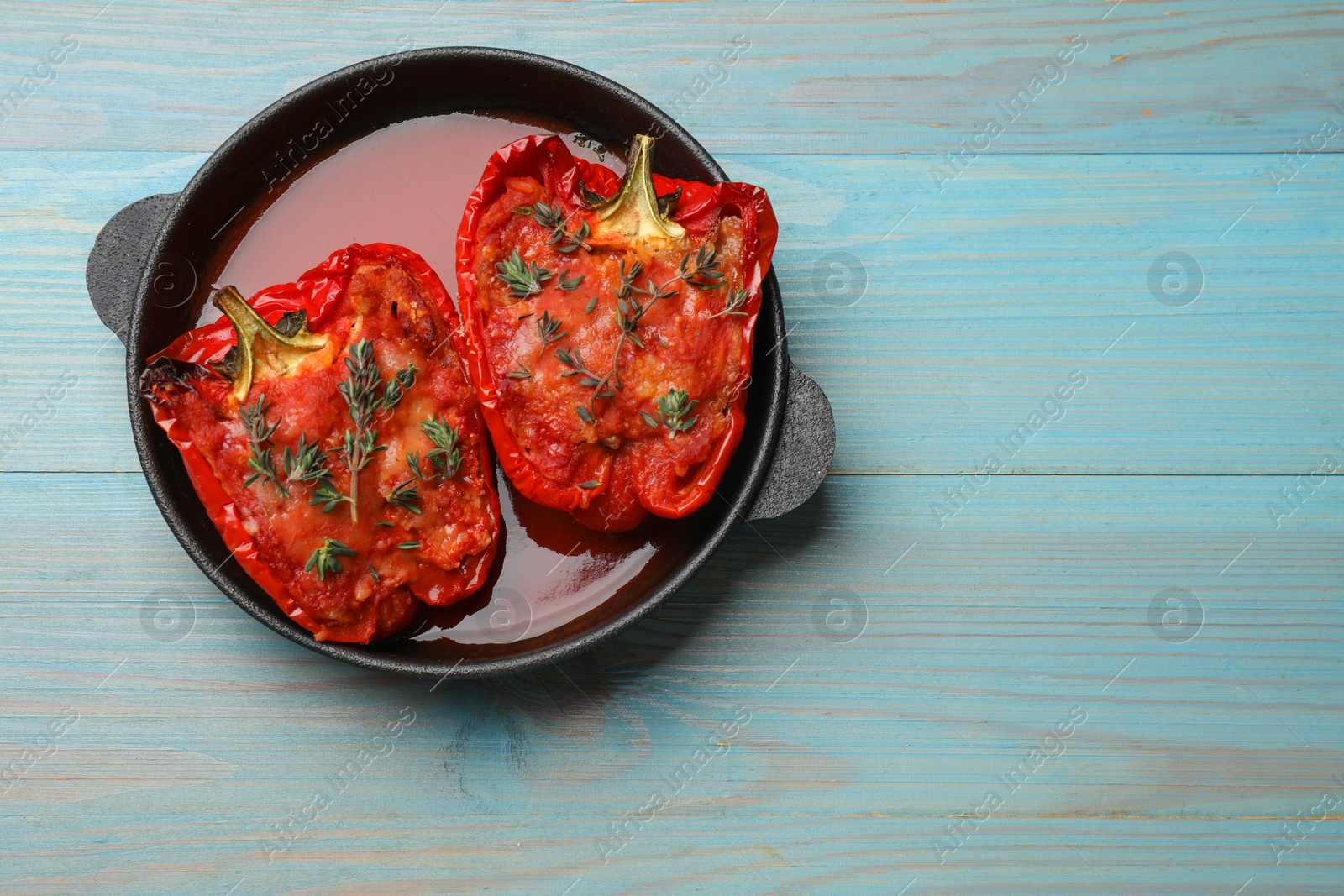 Photo of Tasty stuffed peppers in dish on light blue wooden table, top view. Space for text