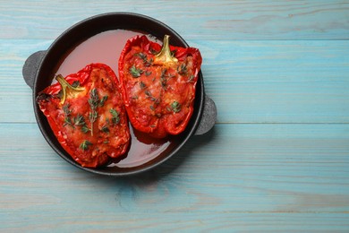 Photo of Tasty stuffed peppers in dish on light blue wooden table, top view. Space for text