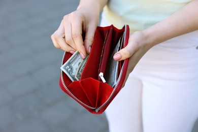 Photo of Woman holding purse with banknotes outdoors, closeup