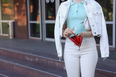 Photo of Woman holding purse with banknotes outdoors, closeup. Space for text