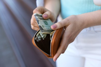 Woman holding purse with banknotes outdoors, closeup