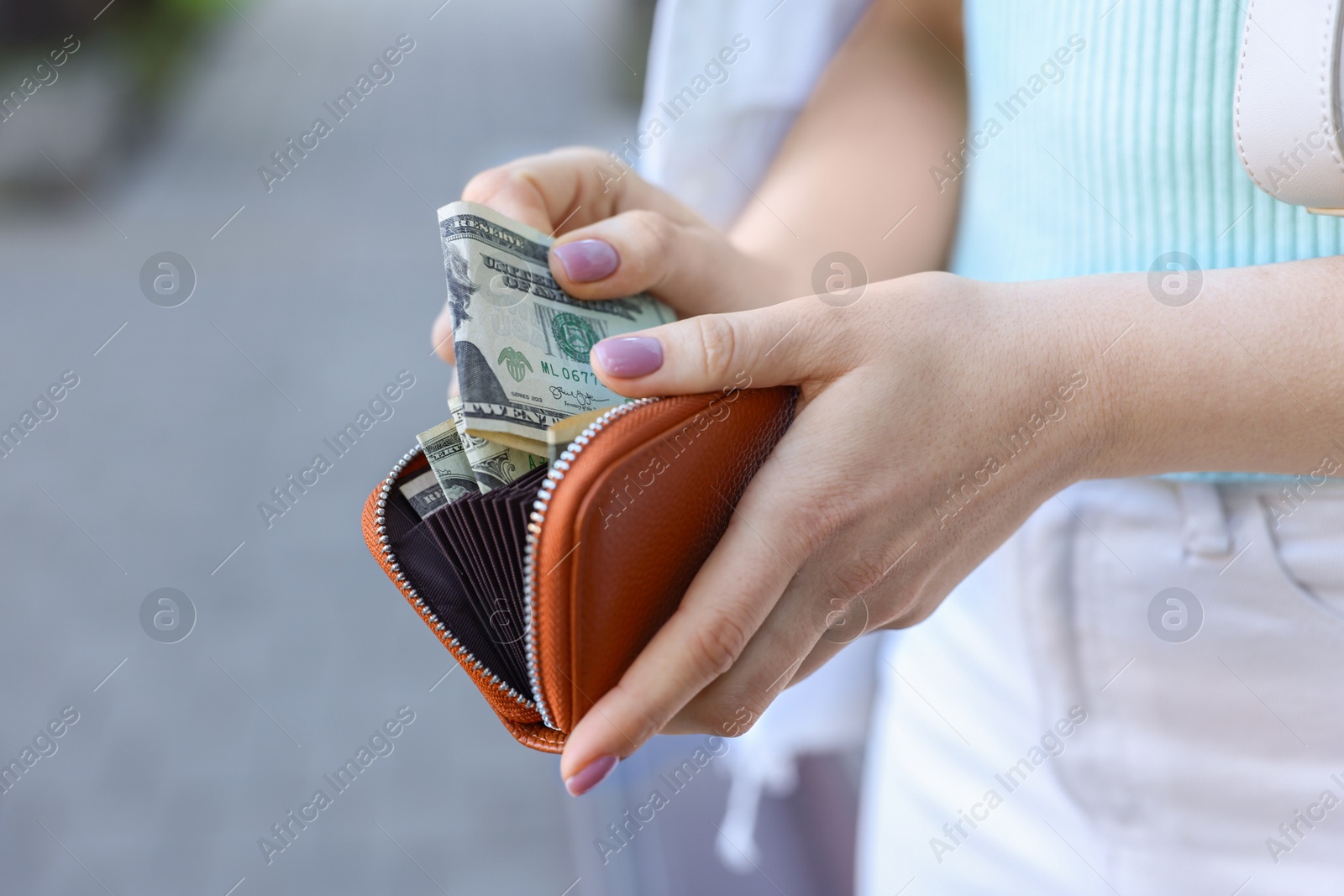 Photo of Woman holding purse with banknotes outdoors, closeup