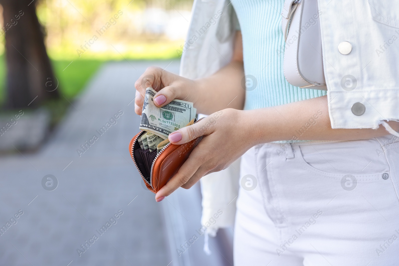 Photo of Woman holding purse with banknotes outdoors, closeup. Space for text