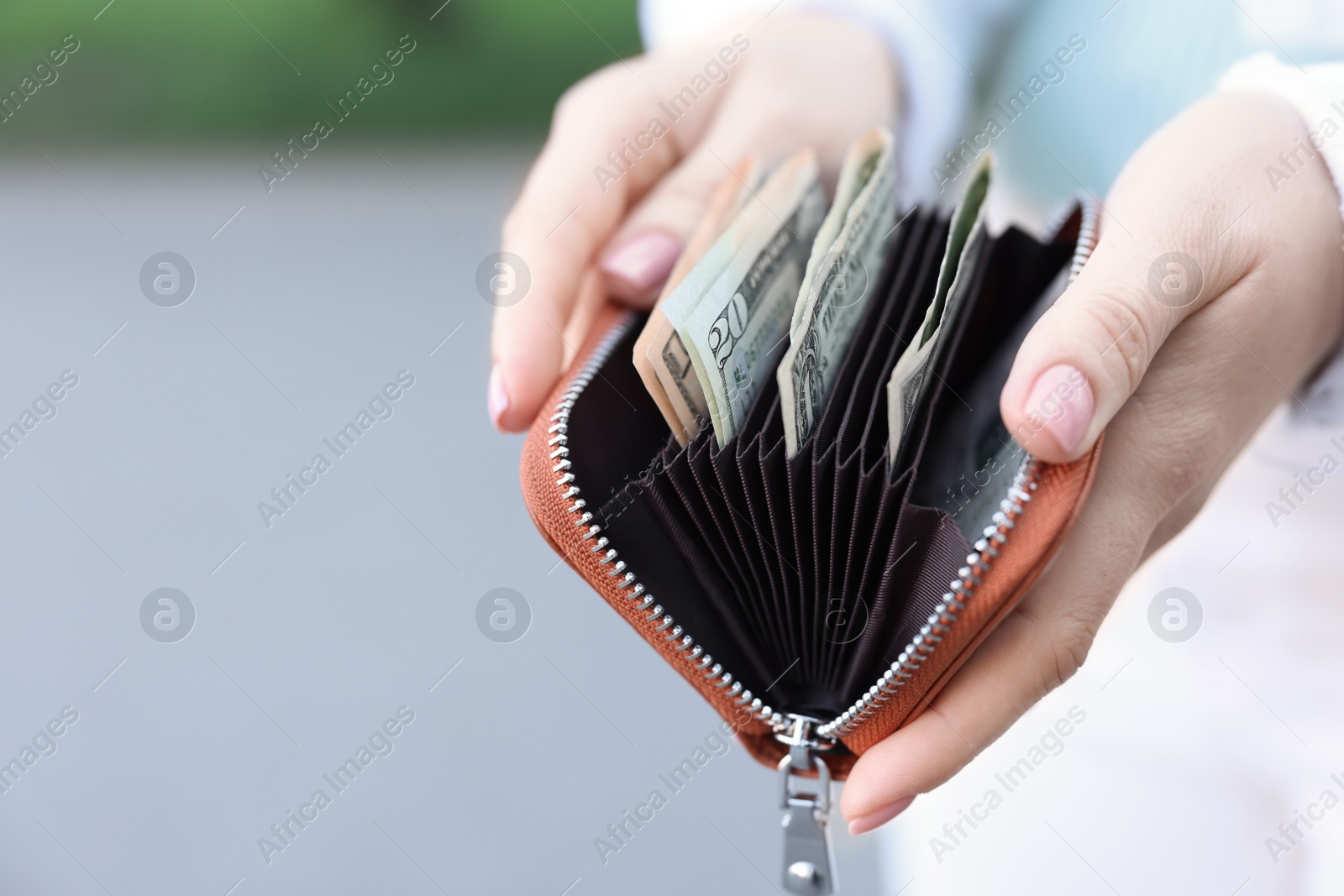 Photo of Woman holding purse with banknotes outdoors, closeup. Space for text