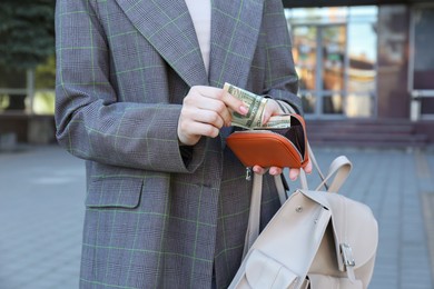 Woman holding purse with banknotes outdoors, closeup