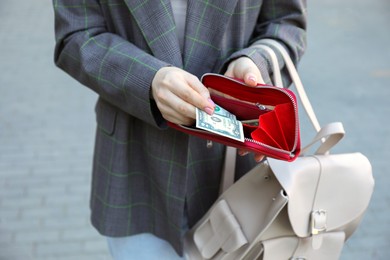 Woman holding purse with banknotes outdoors, closeup