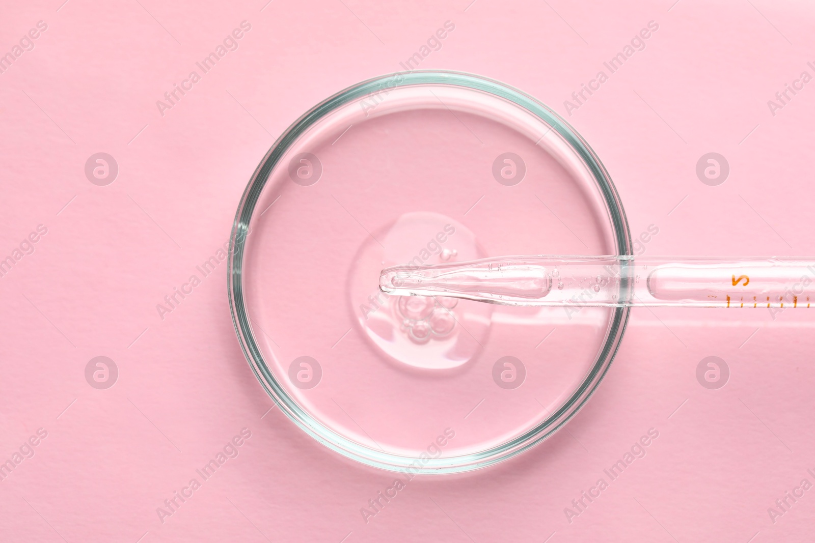 Photo of Glass pipette and petri dish with liquid on pink background, top view