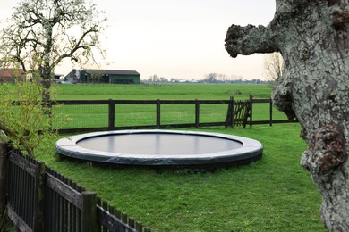 Photo of Spacious backyard with trampoline and wooden fence in early morning