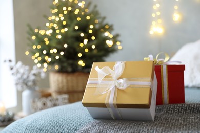 Photo of Christmas gift boxes on bed in festive interior