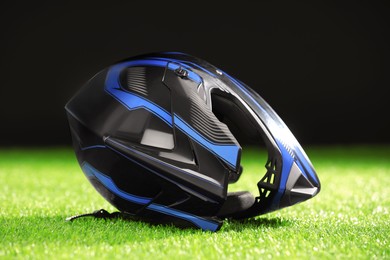 Modern motorcycle helmet with visor on green grass against black background