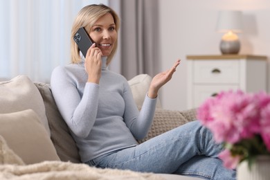 Photo of Happy woman talking on phone at home