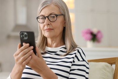 Senior woman using mobile phone at home