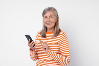 Senior woman with phone on light grey background