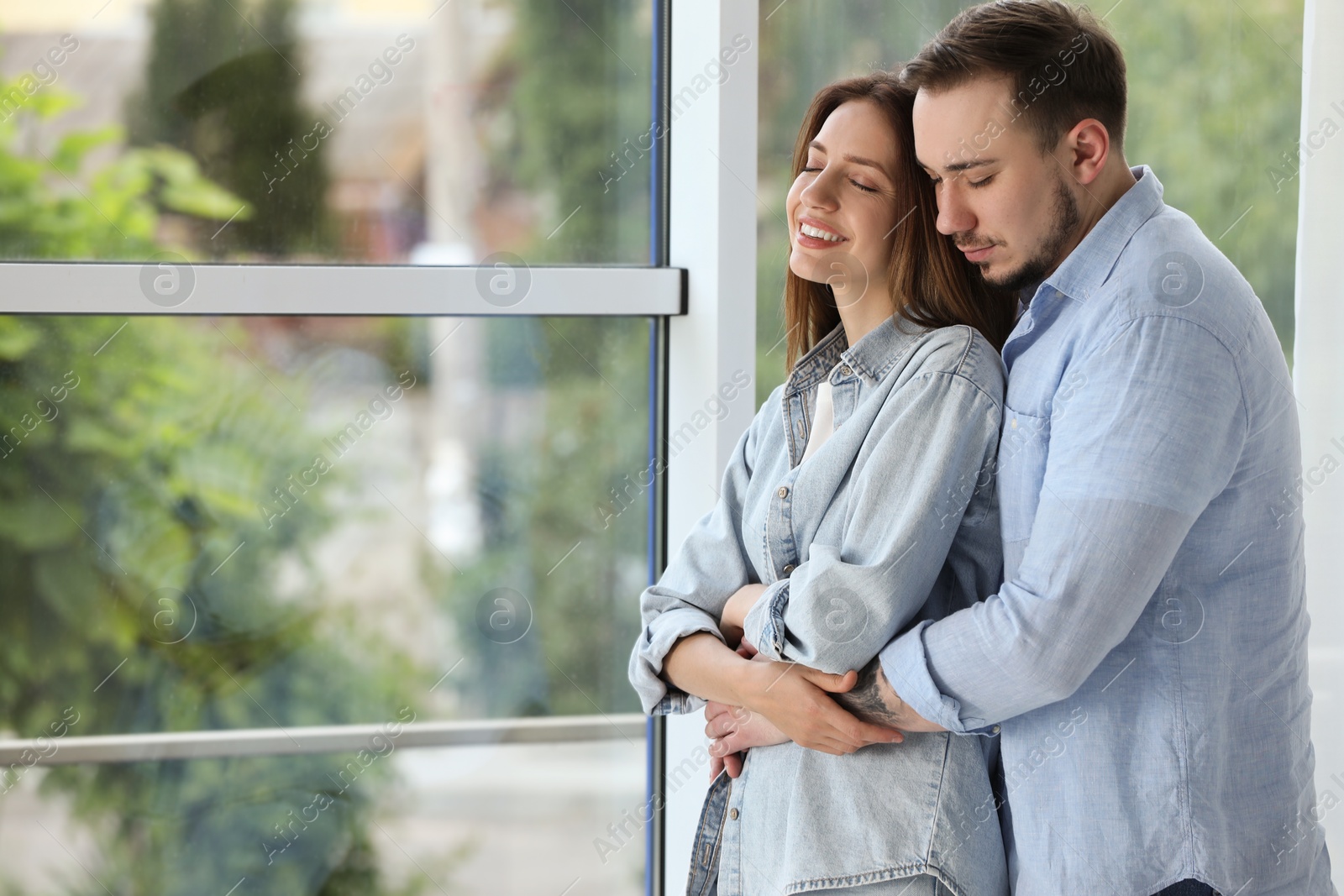 Photo of Cute couple hugging at home. Space for text