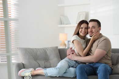 Man hugging his happy girlfriend on sofa at home