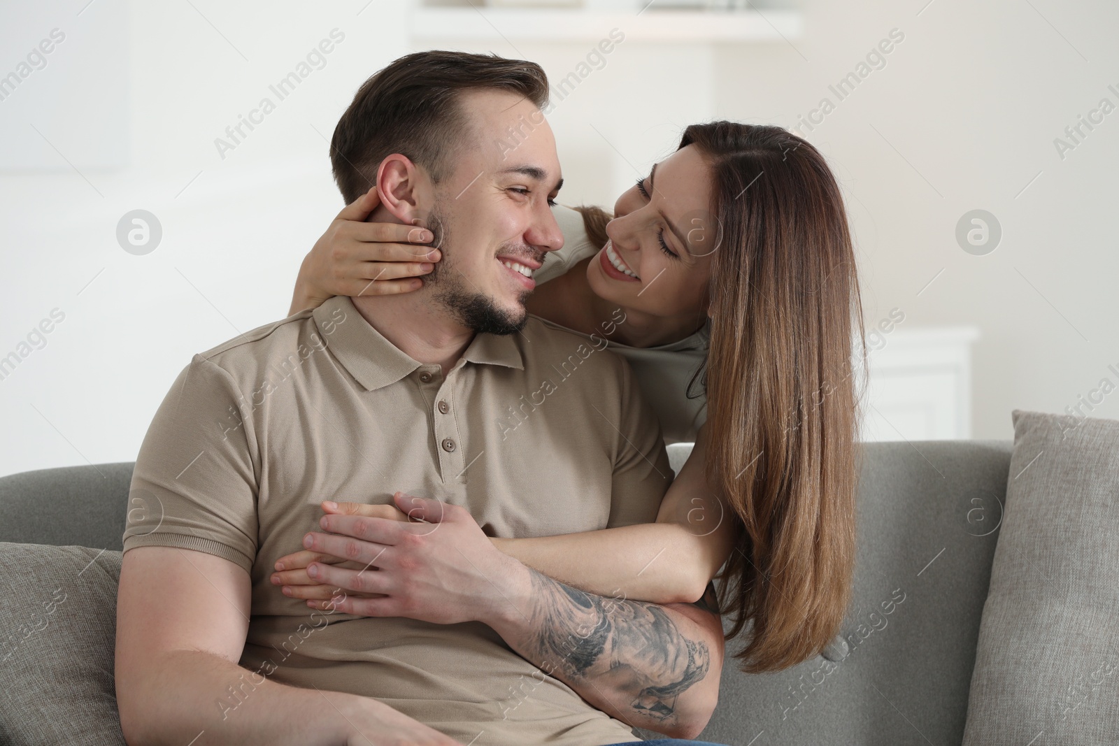 Photo of Woman hugging her happy boyfriend on sofa at home