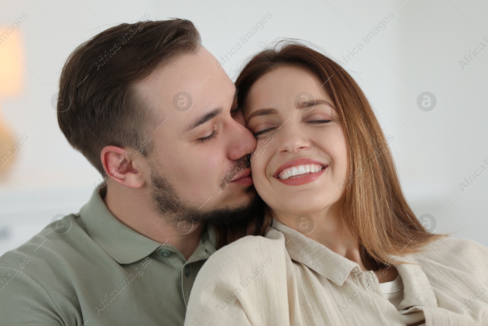 Photo of Man kissing his happy girlfriend at home